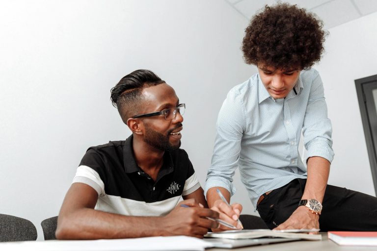 Two coworkers collaborating at a desk, emphasizing teamwork and idea sharing.